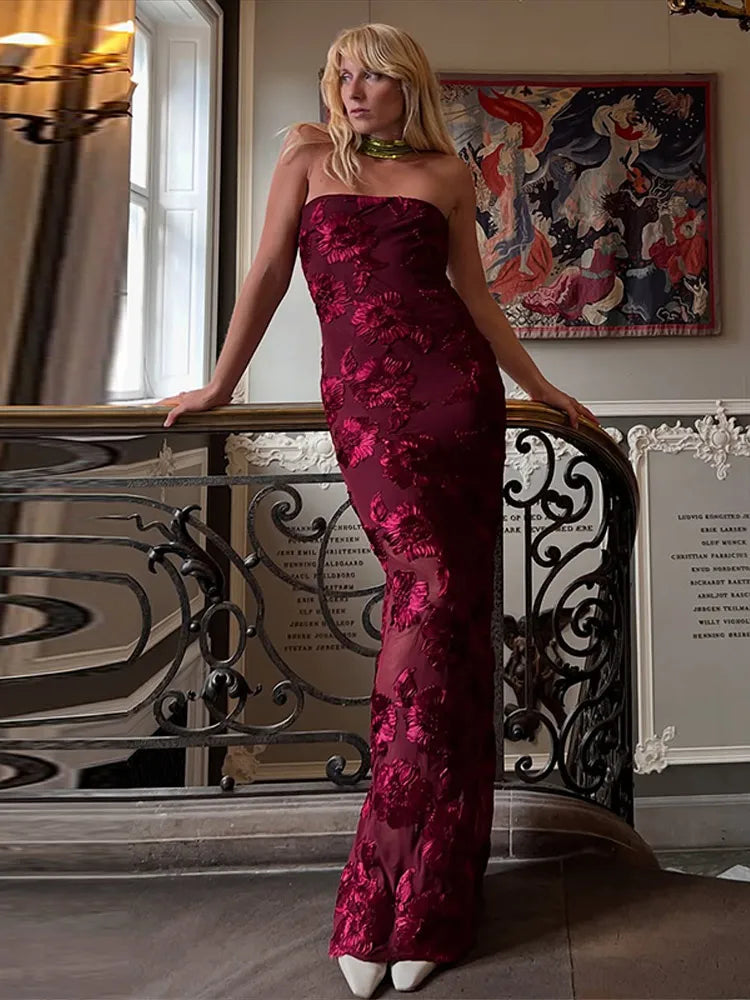 Woman in a red floral dress standing in an elegant interior setting.