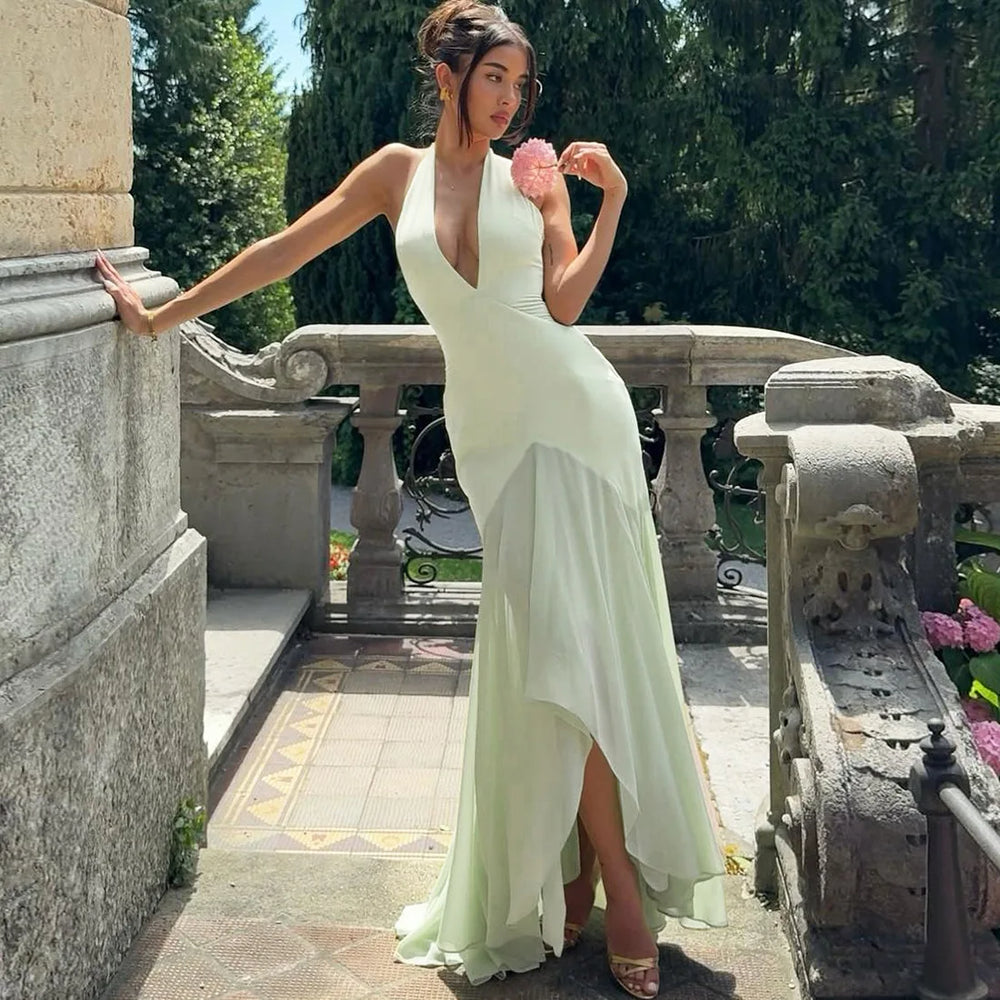 Woman in a white evening gown standing on a stone staircase with greenery in the background