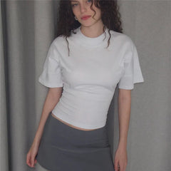 Person wearing a white t-shirt and gray skirt against a plain background