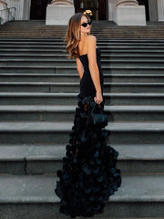 Woman in a black evening gown with a floral skirt standing on steps.