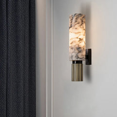 A sleek modern marble wall sconce with warm LED light illuminating a minimalist bedroom. D