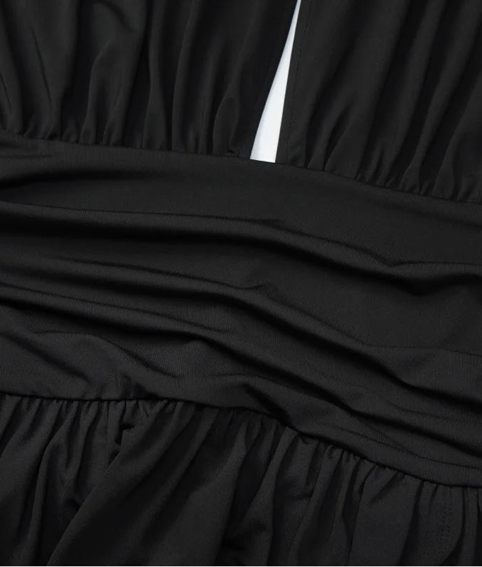 Close-up of a black strapless dress with a plain background