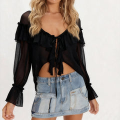 Woman wearing a black ruffled top and denim skirt on a white background