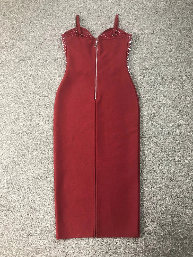 Red dress with embellishments on straps laid flat on a textured surface