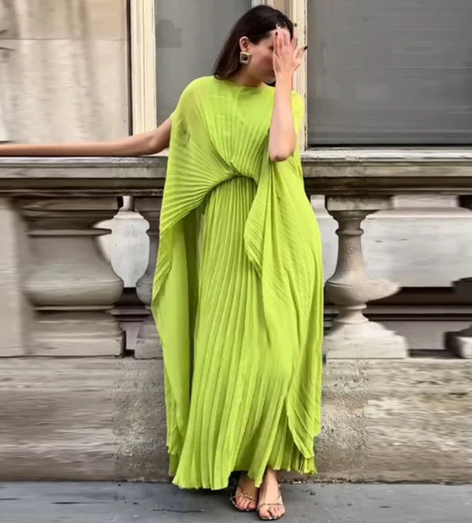 Woman wearing a bright green saree standing against a blurred architectural background