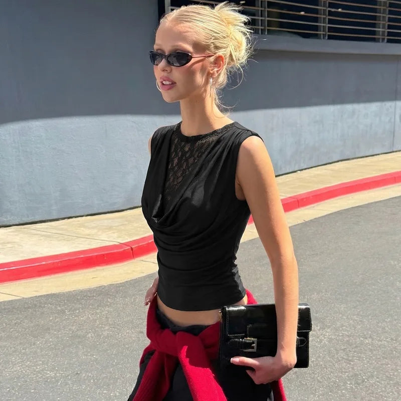 Woman in black top and red skirt with sunglasses and a handbag on a street.
