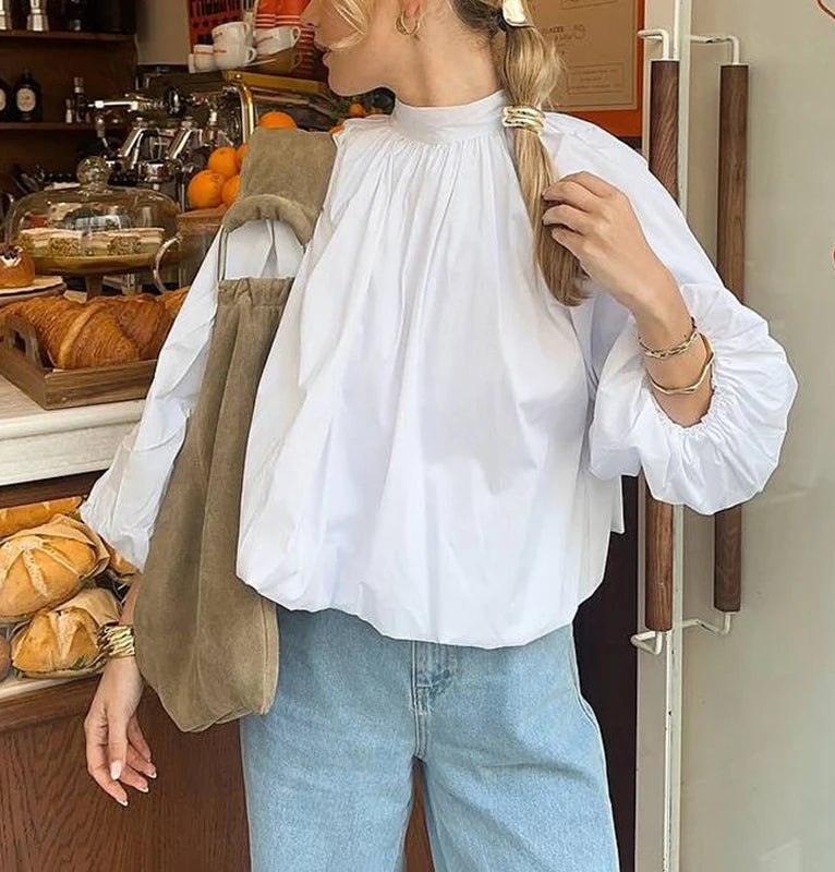 Person wearing a white blouse and blue jeans in a bakery setting