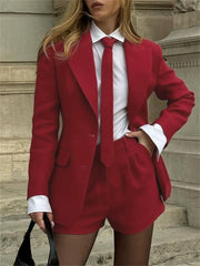 Person wearing a red suit with a white shirt and tie against a stone wall background