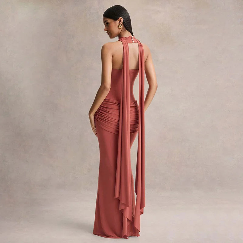 Woman wearing a long, elegant dress with a draped design against a neutral background