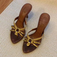 Pair of brown sandals with gold straps on a textured surface