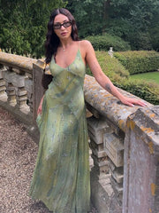 Woman in a green dress standing on a stone wall with a garden background