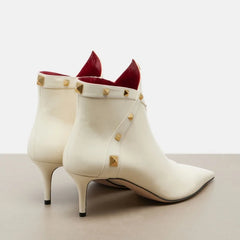 White leather pointed toe ankle boots with gold studs, rear view.