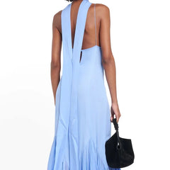 Light blue dress with open back held by a person on a white background