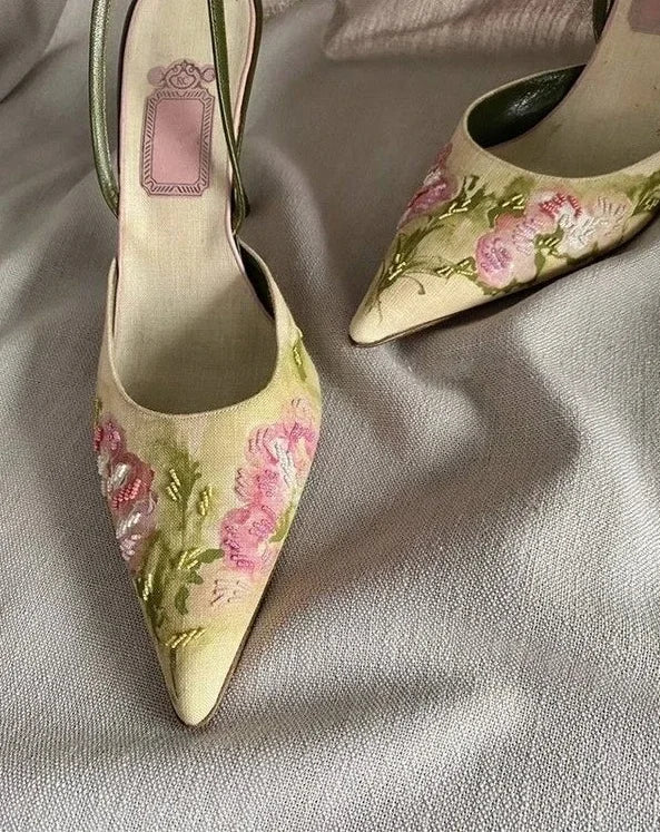 Pair of floral embroidered high-heeled shoes on a light fabric background