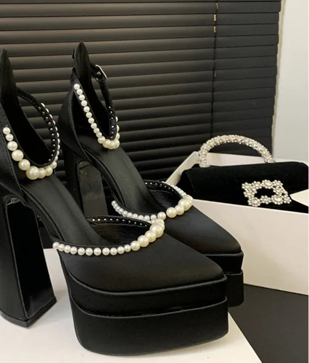 Black high-heeled shoes with pearl detailing on a Celine box.