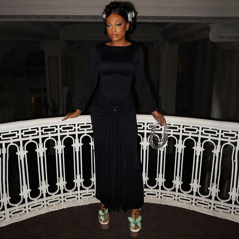 Woman in a black dress standing on a balcony with a white railing.