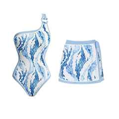 One-shoulder one-piece swimsuit with blue scale print and a metal ring detail, paired with a tie-front mini skirt.