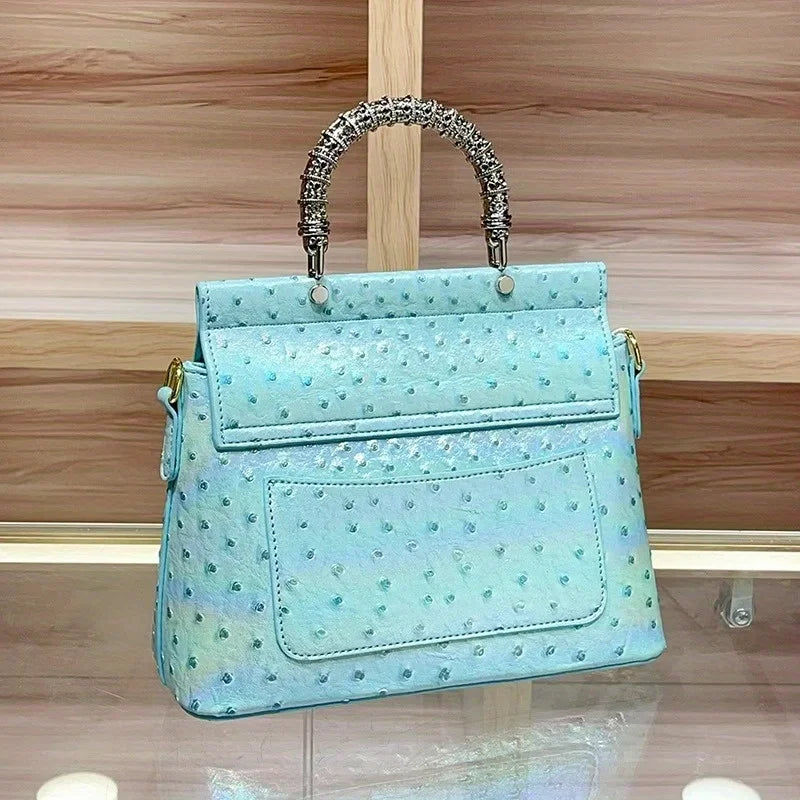 Rear view of the blue ostrich print textured handbag, showcasing a pocket detail.