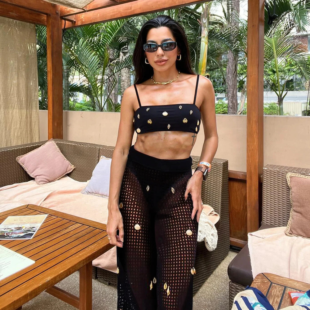 Black embellished bikini top and sheer cover-up pants on a person.