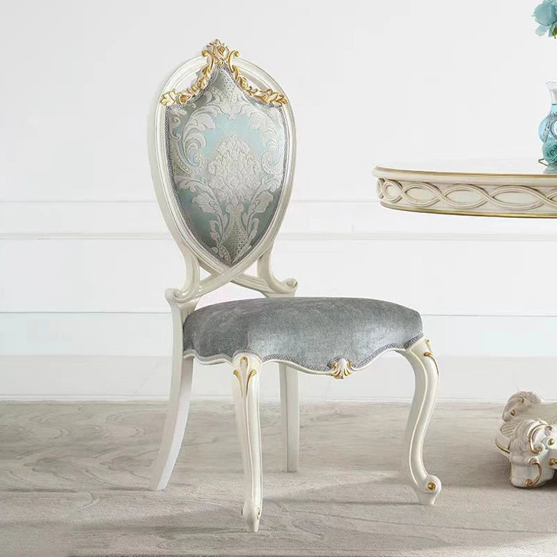 Decorative chair with ornate backrest and gray cushion on a light wooden floor.
