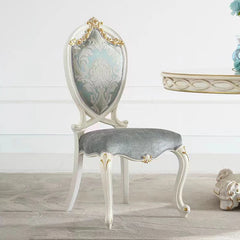 Decorative chair with ornate backrest and gray cushion on a light wooden floor.