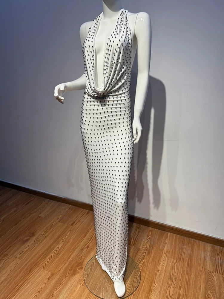 Mannequin wearing a beaded evening gown on a wooden floor with a plain wall background