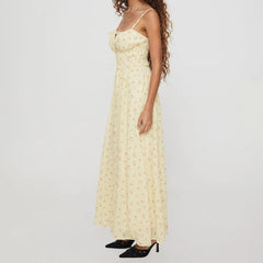 Woman wearing a long, light-colored floral dress on a plain background