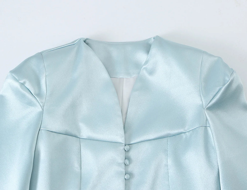 Close-up of the v-neckline and button detail on a light blue satin blazer