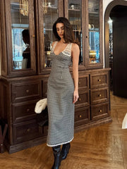 Woman in a checkered dress standing in a room with wooden furniture.