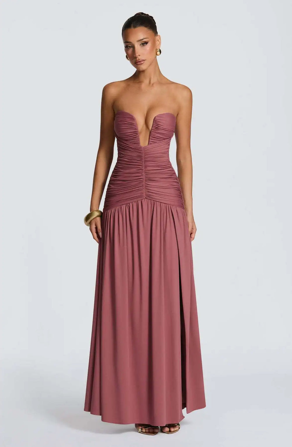 Woman wearing a strapless, long, mauve dress on a white background