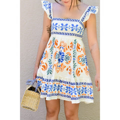 Woman wearing a colorful dress with floral patterns against a neutral background