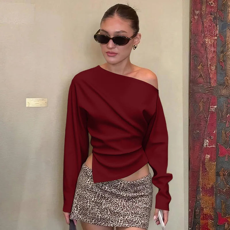 Woman wearing a burgundy off-shoulder top and patterned skirt indoors.