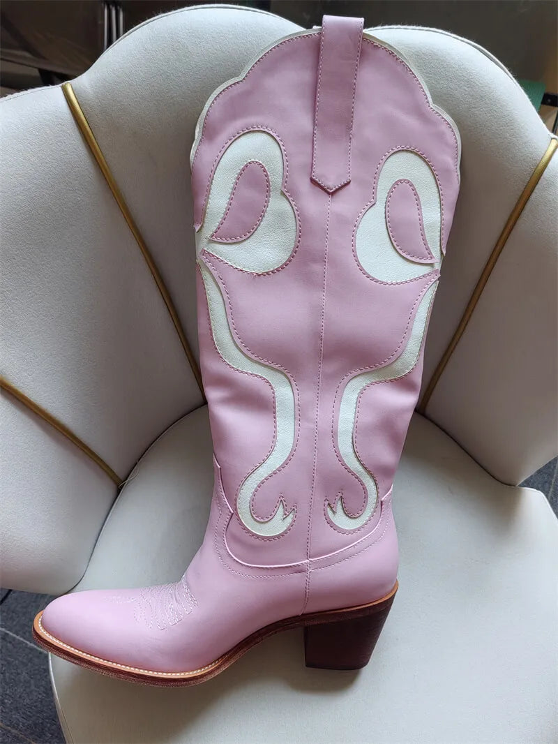 Pink cowboy boot with white embroidery on a mannequin foot.
