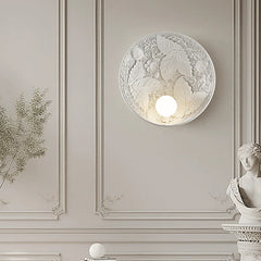 A round French wall sconce with a milk white glass lampshade, casting a soft glow in a cozy bedroom. C