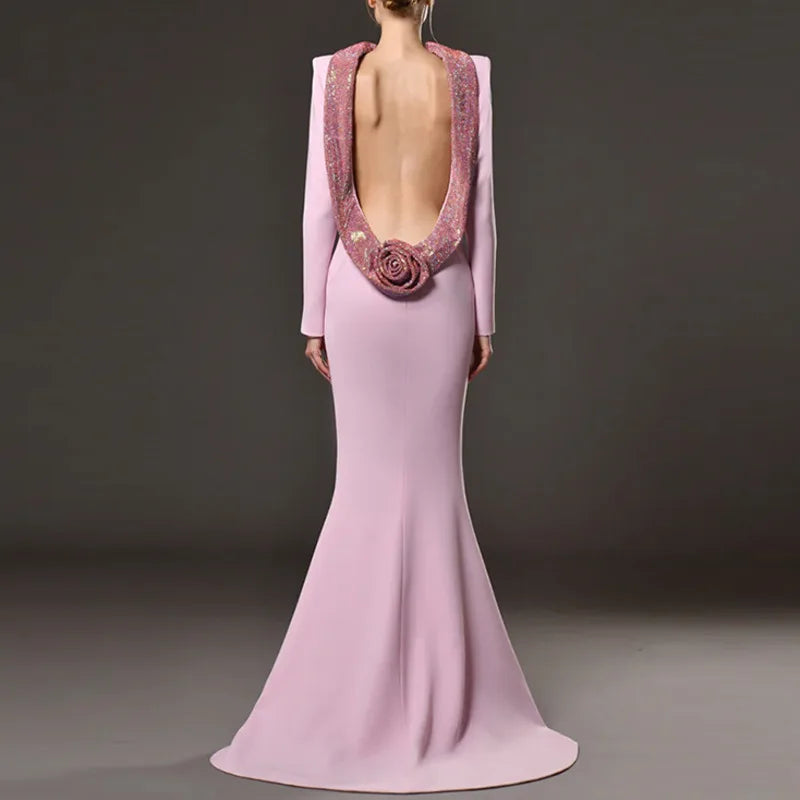 Pink evening gown with open back and floral detail on a dark background