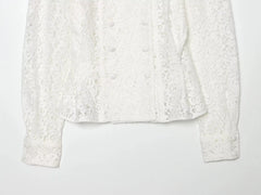 Detail of the hem and sleeves on a white lace double-breasted cropped jacket.