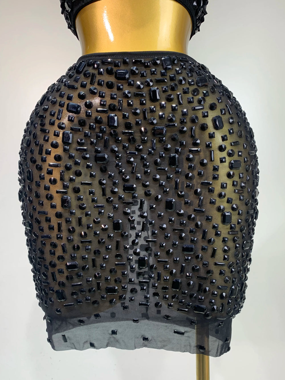 Black beaded skirt on a mannequin against a plain background