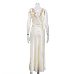 Mannequin wearing a cream-colored evening gown with sheer sleeves on a white background