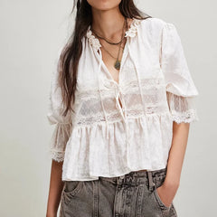 White lace blouse worn by a person on a plain background