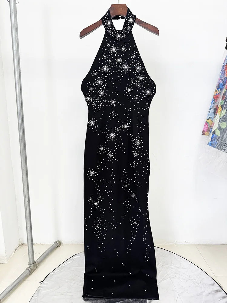 Black dress with star pattern on a hanger against a white background