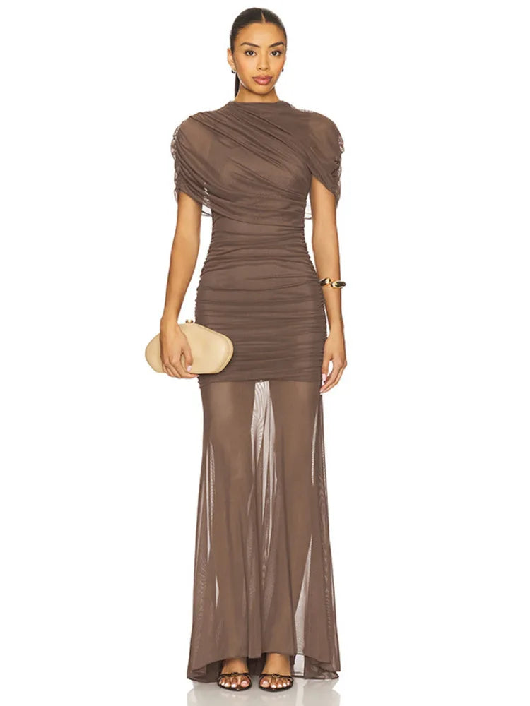 Woman wearing a brown evening gown with sheer overlay on a white background