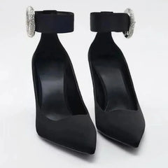 Pair of black pointed toe pumps with rhinestone ankle strap buckle.
