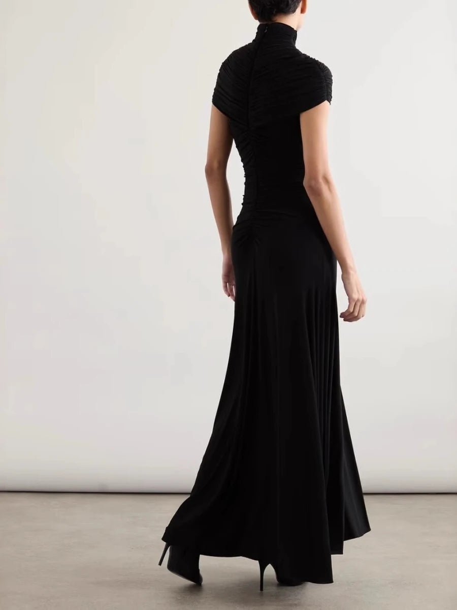 Person wearing a black dress with a plain background