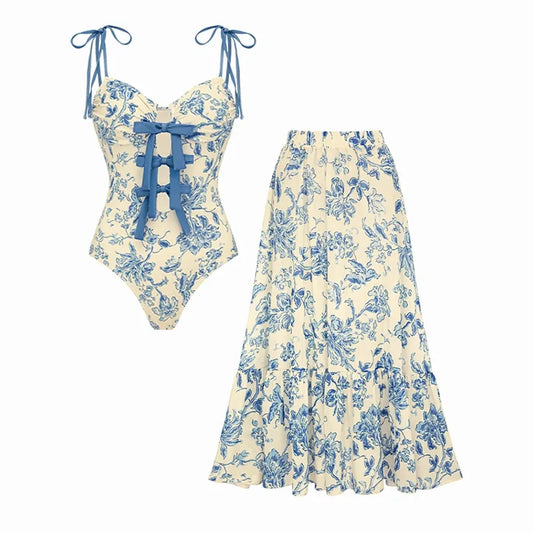 Flat lay of a blue floral print one-piece swimsuit and a matching flowing skirt.