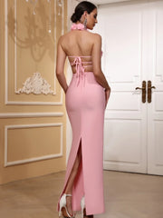 Woman wearing a pink evening gown with a high slit in a decorated room.
