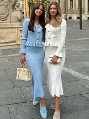 Two women posing together on a city street, wearing stylish outfits.