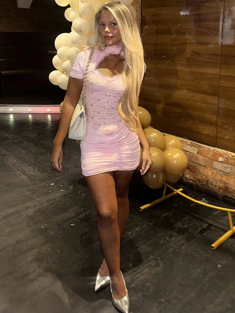 Woman in a pink dress standing in front of balloons with a wooden wall background