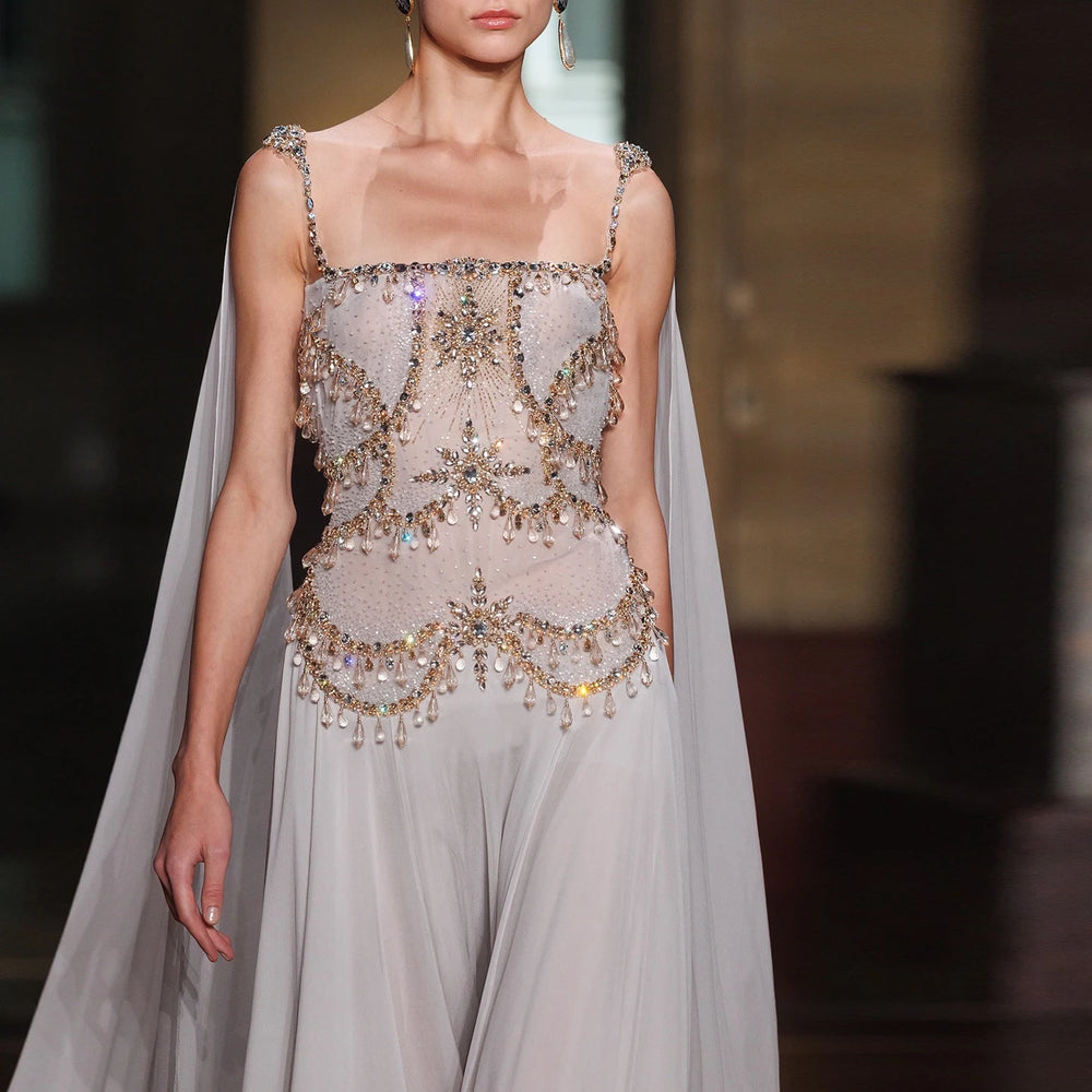 Model wearing a glamorous dress with intricate embellishments on a blurred background