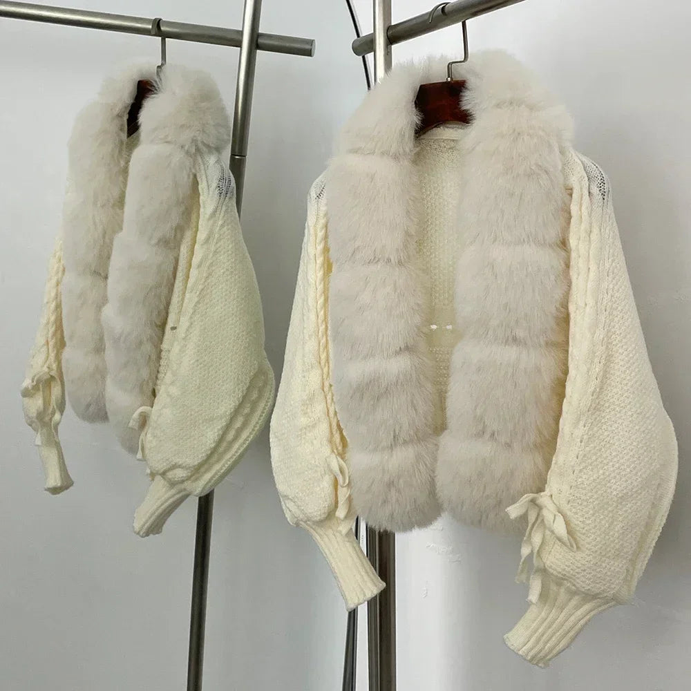 White fur vest with a white sweater underneath on a rack against a plain background
