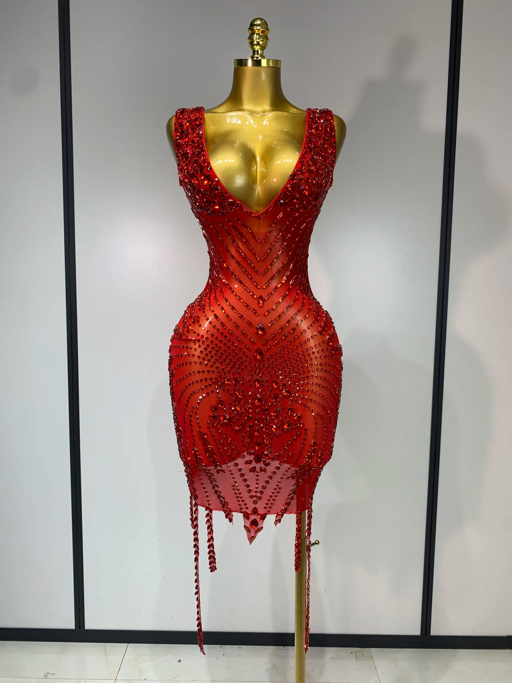 Red beaded dress on a mannequin against a plain background